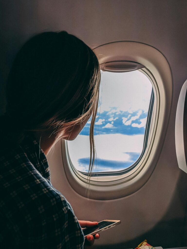 The moment before arrival: a woman gazes out her airplane window at a vast expanse of clouds, suspended in anticipation of discovering "Why Barcelona