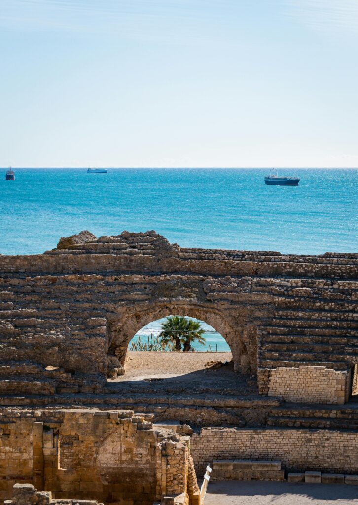 The vast blue Mediterranean Sea seen through the ancient arches of Tarragona's Roman amphitheater, where millennia of history meet the timeless sea.