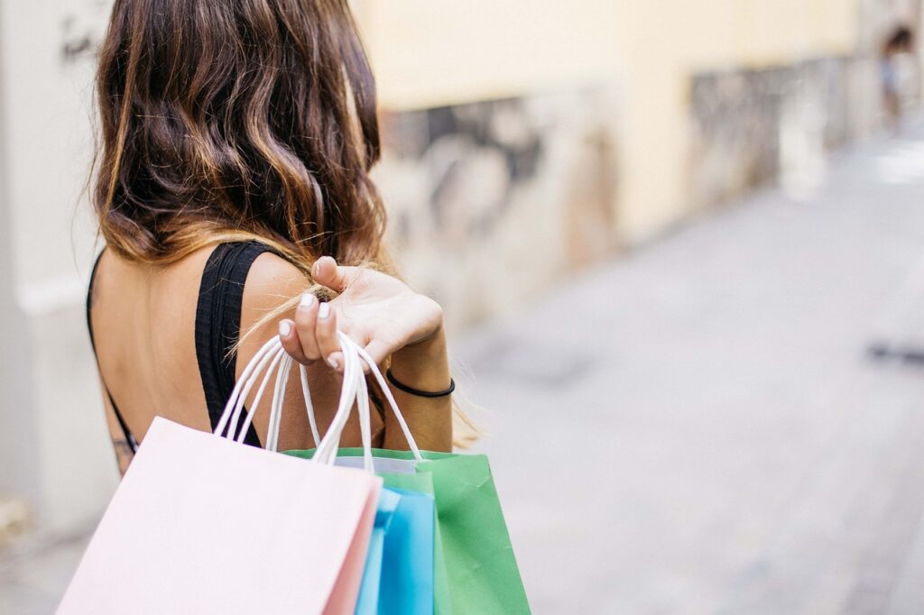 Back view of a woman carrying stylish shopping bags, likely from a boutique or gift shop, representing contemporary Spanish life beyond the common stereotypes about Spain.