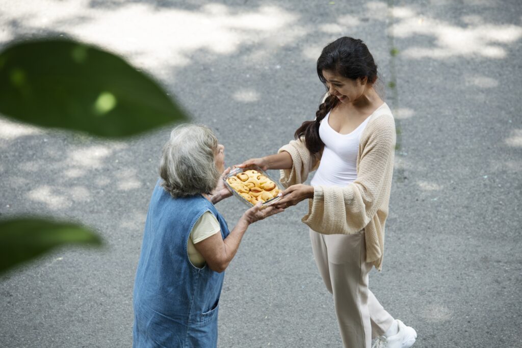 A young woman smiling warmly as she hands a homemade cake to an elderly neighbor, showcasing local community spirit in Barcelona.