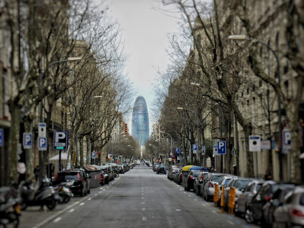 The Torre Agbar seen at the end of an avenue lined with bare trees in winter.