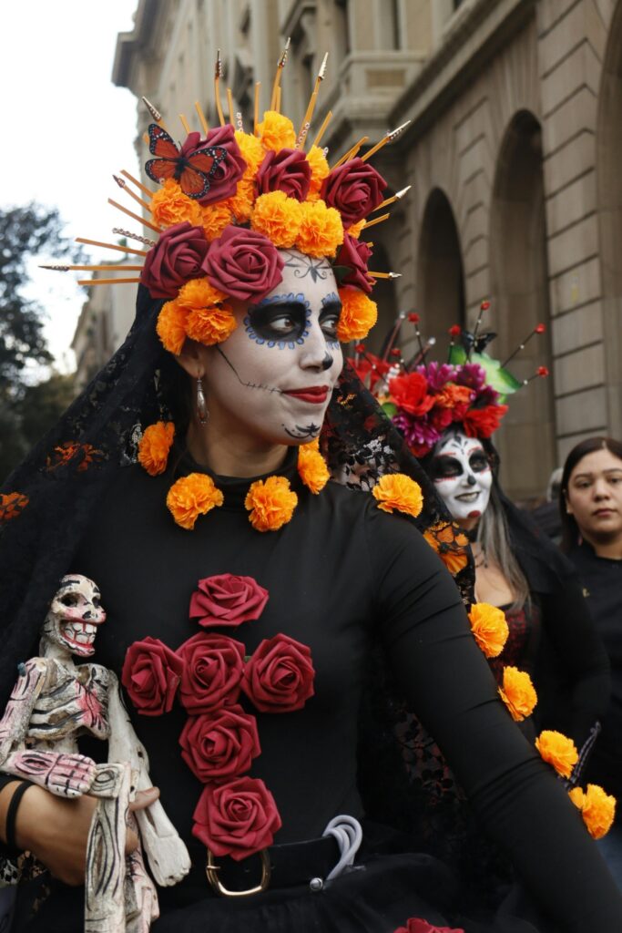 Celebrating Día de Muertos in Barcelona: people dressed as elegant Catrinas walk down a city avenue. Surprising events like this happen when you explore Barcelona year round.